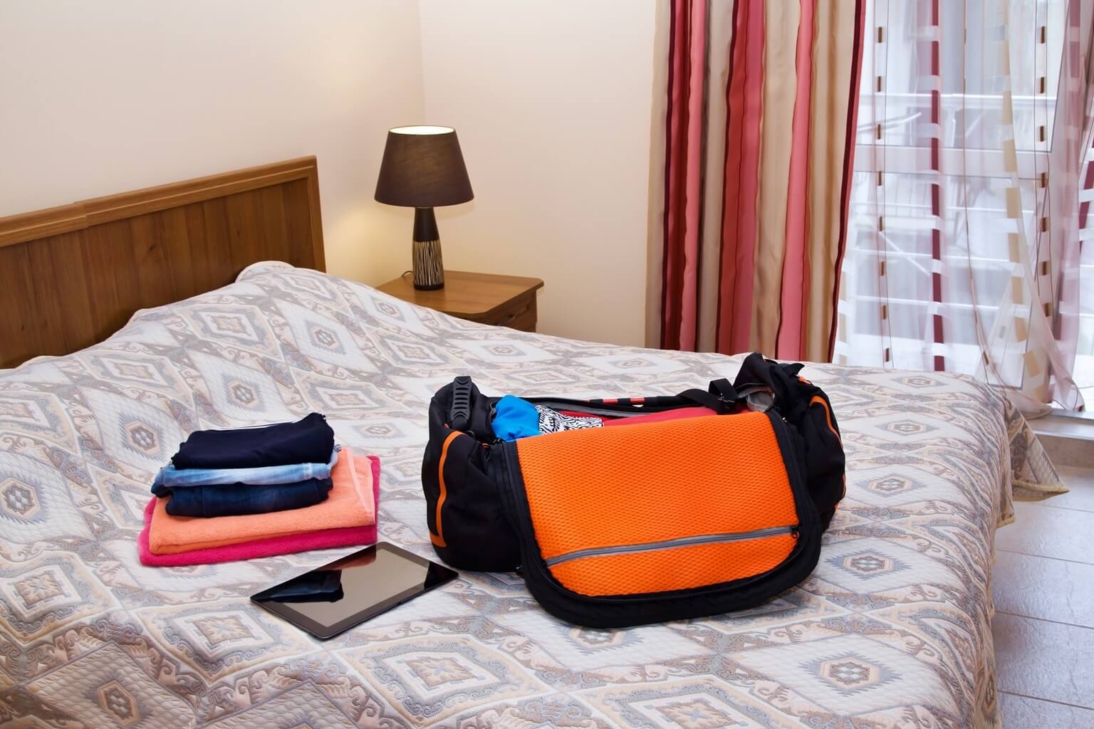 Logement en Irlande : Chambre d'hôtel avec bagage ouvert, linge et tablette